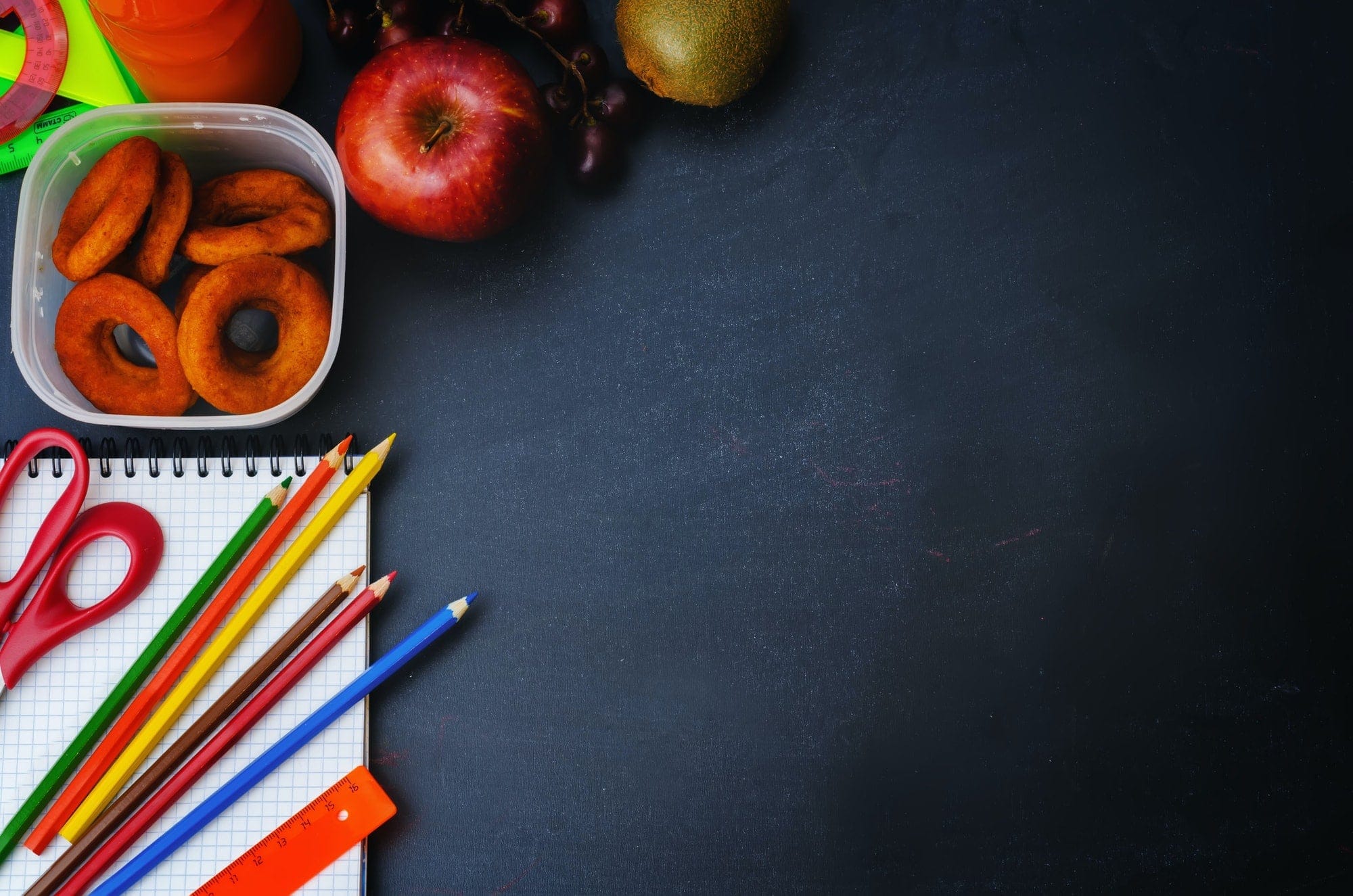 School background with school lunch, pencils and a notebook.